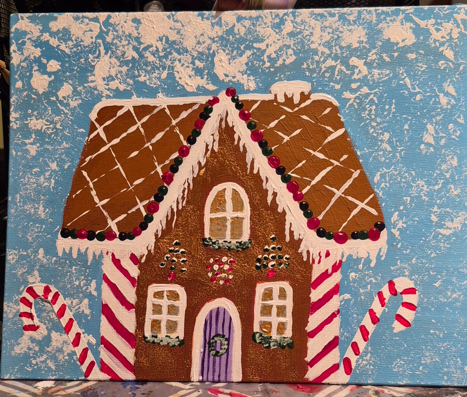 Gingerbread house in falling snow painting on a textured blue background