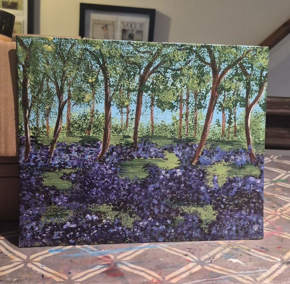 Painting of a forest scene with a carpet of purple bluebells on a canvas board